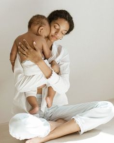 a woman sitting on the floor holding a baby