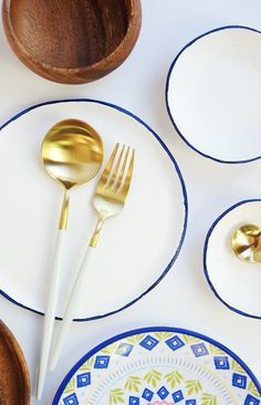 a white table topped with plates and gold utensils