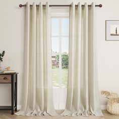 a white curtain hanging in front of a window with a wooden table next to it