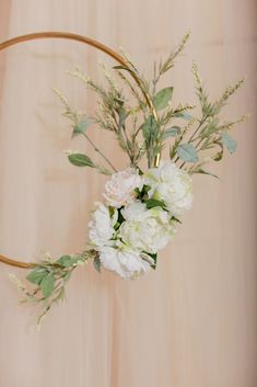 a vase with flowers and greenery is hanging on the wall in front of a curtain