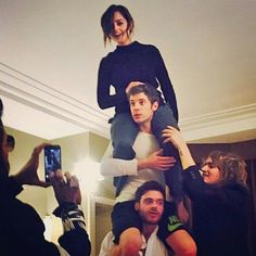 a woman is sitting on top of a man's head while people take pictures