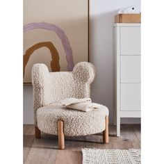 a sheep - like chair sits in front of a dresser with a pillow on it