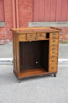 an old wooden desk with drawers on the side walk next to a red brick building