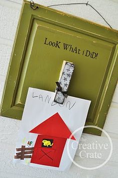 a green frame hanging on the wall with a paper cut out of it and a red barn