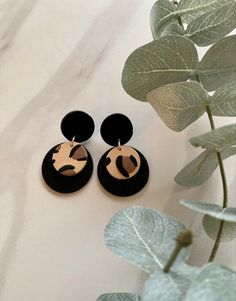 the black and gold earrings are next to a plant