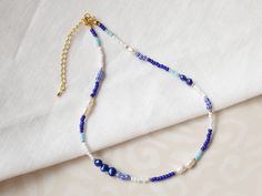 This blue beaded necklace is a lovely necklace with blue and white beads and pearls. In this gold-plated necklace, I have paired blue, white, gold and striped seed beads with genuine white and blue freshwater pearls. The beading wire I use is flexible high-quality stainless steel, composed of multiple twisted tiny wires that are nylon coated to protect the beads. The length of the necklace is 15 inches (38 cm), with a 2,5 inches (6 cm) extension chain - so you can adjust the length of your necklace between 15 inches and 17.5 inches (38 - 44,5 cm). If you would like to have the necklace shorter or longer, just send me a message - I'm happy to personalize this necklace for you. See my whole jewelry collection: https://www.etsy.com/shop/Tazelry ♥ Jewelry care ♥ It's important to keep your jew Blue Pearl Necklace With Tiny Beads As Gift, Blue Pearl Necklace With Tiny Beads For Gift, Blue Pearl Necklace With Colorful Beads For Gift, Blue Dainty Beaded Choker Necklace, Dainty Blue Beaded Choker Necklace, Blue Pearl Necklace With Spacer Beads For Gift, Dainty Handmade Blue Beaded Necklace, Nautical Necklace, Beads Choker