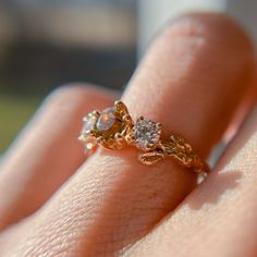 a woman's hand holding an engagement ring with two diamonds on it and one diamond in the middle