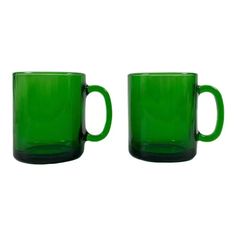 two green coffee mugs sitting next to each other on a white background, one is empty