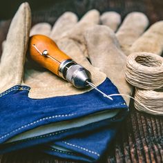 a pair of blue jeans and a sewing needle sitting on top of a piece of cloth