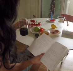 a woman sitting at a table reading a book