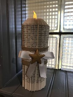 a candle made out of old book pages with a star on the top and ribbon around it