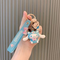 a hand holding a keychain with two cartoon animals on it and a tag attached to it