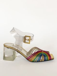 description our classic 70s shoe in a high heel. high shine metallic leather featuring rainbow straps. open square toe with PVC ankle strap and gold buckle closure. clear plexi heel. gold leather lining with leather Italian soles 3" heel colors available rainbow   details Made in Italy Runs true to size. If between siz 70s Shoes, Rainbow Shoes, Rainbow High, Metallic Sandals, Gold Sandals, Gold Leather