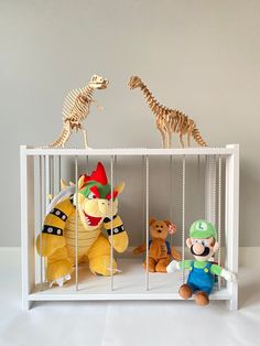 three stuffed animals are in a cage with skeletons on the wall behind them and one is wearing a hat