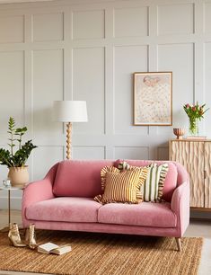 a living room with pink couches and plants in vases on the side table