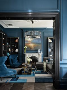 a living room filled with furniture and a chandelier hanging from the ceiling in front of a fireplace