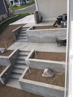 concrete steps leading up to a house with landscaping equipment on the ground in front of it