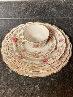 a set of four china plates with floral designs on the rims, sitting on a granite countertop