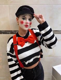 a woman with clown makeup is standing in front of a tiled wall and posing for the camera