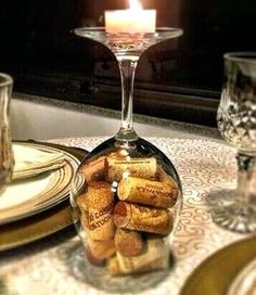 a wine glass filled with corks sitting on top of a table next to a candle