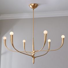 a gold chandelier hanging from the ceiling in a room with white walls and flooring