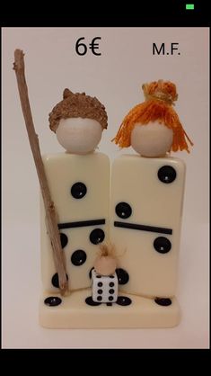 two small figurines sitting on top of a piece of white cake with black dots