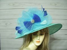 "Gorgeous light aqua wide brim sinamay hat with aqua veiling, aqua and blue accent with a jewel center. the jewel is removable. The brim is oval. This hat is 22.5\" for the inside circumference but does have a hat adjuster on the inside to make it smaller. The brim is about 18\" from one side to the other. Perfect for many events from Kentucky Derby, Easter, Weddings, Mother's Day or anywhere you need a beautiful hat! This hat will ship in a large box to accommodate the size of the brim. Please Formal Blue Hat With Curved Brim, Wide Brim Blue Hat For Western-themed Events, Luxury Elegant Turquoise Hat, Elegant Blue Brimmed Hat, Whimsical Blue Wide-brim Hat, Church Lady Hats, Sinamay Hats, Easter Hats, Kentucky Derby Hat