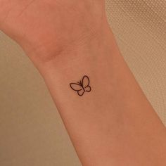 a small tattoo on the wrist of a woman with a butterfly in it's center