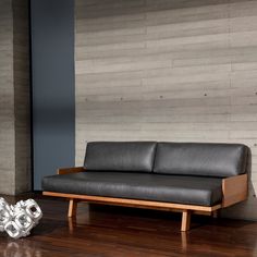 a black leather couch sitting on top of a hard wood floor next to a wall