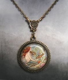 a necklace with an image of a mermaid in the water on it's side