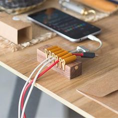 a wooden table topped with electronic devices and wires on top of each other, next to a cell phone