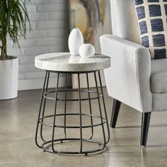 two white vases sitting on top of a table in front of a gray chair