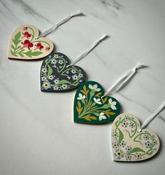 four heart shaped ceramic ornaments on a marble counter top with toothpicks in the shape of flowers and leaves