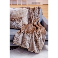 a leopard print blanket sitting on top of a couch next to pillows and a chair