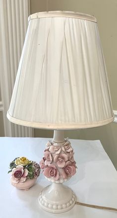 a lamp that is on top of a table next to a vase with flowers in it