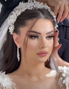 a woman in a wedding dress getting her hair and make - up done by a professional makeup artist