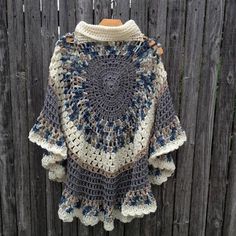 a crocheted sweater hanging on a wooden fence