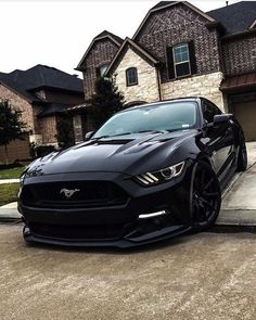 a black mustang parked in front of a house