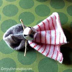 a small knitted object with a bell on it's end sitting on a green surface