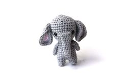 a small crocheted elephant sitting on top of a white surface