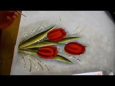 three red tulips are sitting on a table with white paper and scissors next to it