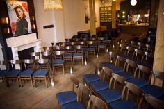 a room filled with lots of blue chairs next to a fire place and a painting on the wall