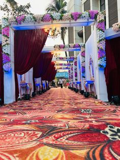 an aisle decorated with flowers and red curtains for a wedding ceremony in the middle of a city