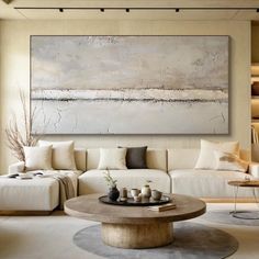 a living room filled with furniture and a large painting on the wall above it's coffee table