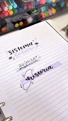 there is a notebook with writing on it next to markers and pens in the background