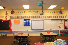 an empty classroom with desks and chairs in front of a whiteboard on the wall