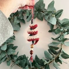 a person holding a crocheted christmas ornament in front of a wreath