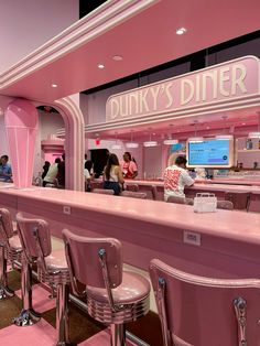 people are standing at the pink diner counter in front of the tv screen and chairs