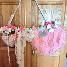 a door hanger decorated with pink and white laces, flowers, and bows