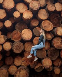 a woman sitting on top of a pile of logs